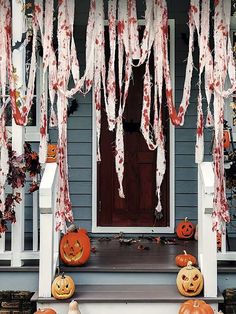 a porch decorated for halloween with pumpkins and icicles hanging from the front door