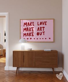 a pink poster hanging on the wall above a wooden cabinet in a room with hardwood floors