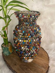 a potted plant sitting on top of a wooden stand next to a vase filled with glass beads