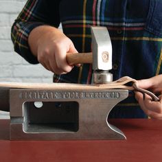 a person using a hammer to cut wood on a piece of plywood with a vise