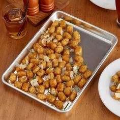 there is a pan full of tater tots on the table next to some drinks