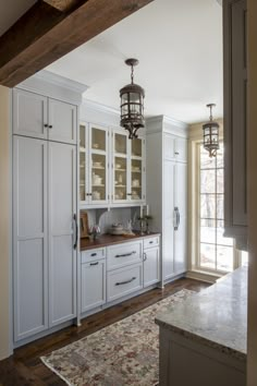 a kitchen with lots of white cabinets and wood flooring on the side of it