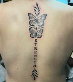 a woman's back with a butterfly tattoo on her left shoulder and the words strength written in cursive letters