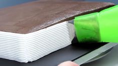 someone is using a knife to cut out a book with chocolate on the pages and green glue