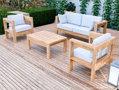 an outdoor patio furniture set on a wooden deck with plants in the backgroud