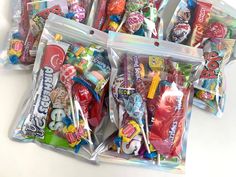 several bags filled with candy sitting on top of a white table next to each other