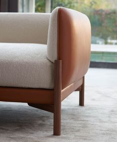 the back end of a couch with a wooden frame and arm rest on carpeted flooring