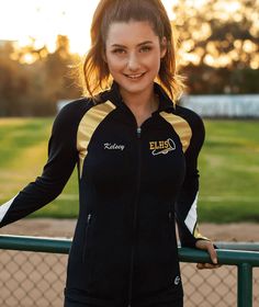 a woman standing in front of a fence with her hands on her hips and smiling at the camera