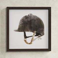 an old helmet mounted on the wall above a wooden framed artwork piece in a black frame