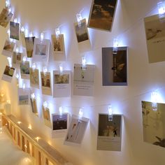 there are many pictures on the wall with lights around them and some cards attached to the wall