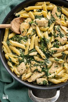 a skillet filled with pasta, chicken and spinach