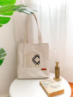 a white bag sitting on top of a table next to a vase and bookcase