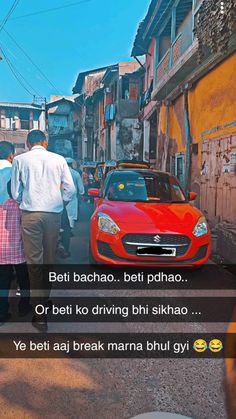 two people walking down the street in front of a red car