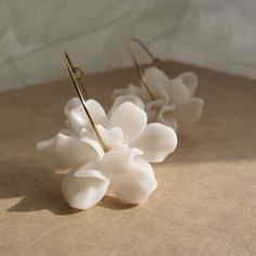 two white flower shaped earrings on top of a table