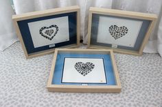 three framed pictures with hearts cut out of paper in the shape of a heart are sitting on a table