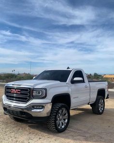 a white truck parked on top of a dirt field