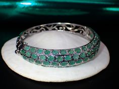 This fabulous little vintage treasure is a hinged natural emerald bangle bracelet that features 68 beautiful light green natural oval cut pave set emeralds. It measures approx. 6.75" inches in circumference, 2-1/4" inside opening and up to 1/2" wide. It weighs 22.76 grams. The bracelet is functioning and secure. Please bear in mind this is a previously owned and loved vintage treasure which shows signs of wear. Please inspect all photos prior to purchase. Items $100 or more are shipped in a high Luxury Green Oval Bracelet, Luxury Green Gemstone Bangle, Exquisite Green Jewelry With Pave Setting, Luxury Oval Gemstone Bangle, Green Bangle For Formal Occasions, Fine Jewelry Style, Elegant Oval Green Bangle, Elegant Green Oval Bangle, Oval Emerald Bracelets For Anniversary, Oval Gemstone Bangle In Fine Jewelry Style