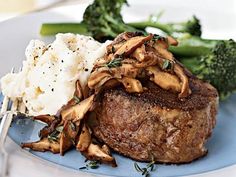 a blue plate topped with steak, mushrooms and mashed potatoes next to broccoli