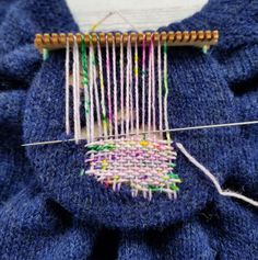 a close up of a piece of cloth with yarn on it and a needle in the middle