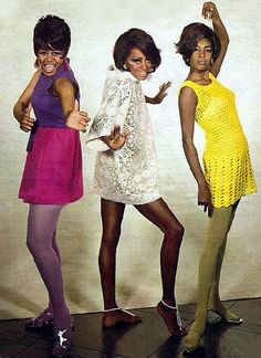 three women in dresses and tights posing for the camera with their hands up to one another