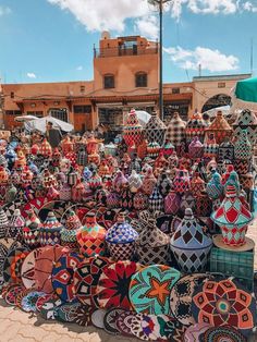 many colorful vases are on display in front of an adobe - style building,