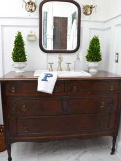 a bathroom with a large mirror above the sink and an antique dresser in front of it