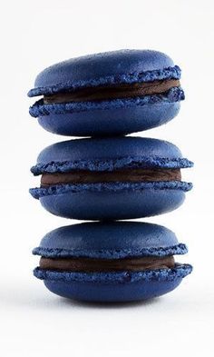 three blue macaroons stacked on top of each other with chocolate filling and frosting