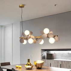 a dining room table and chairs with lights hanging from the ceiling