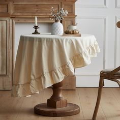 a table with a white vase on top of it and a wooden chair next to it