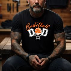 a man sitting on a bench wearing a basketball dad t - shirt