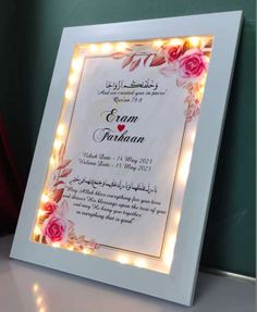 a wedding card with roses and lights in the frame on top of a table next to a