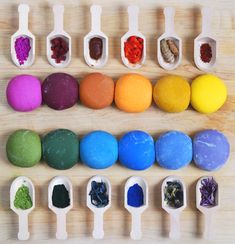 several spoons filled with different types of colored powder on top of a wooden table