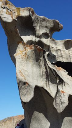 a large rock formation in the middle of a desert area with people standing around it