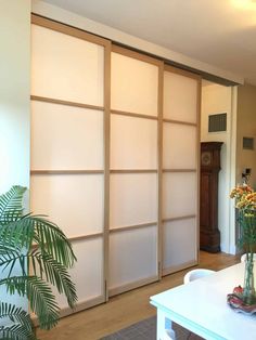 a living room with sliding doors and flowers in vases on the table next to it