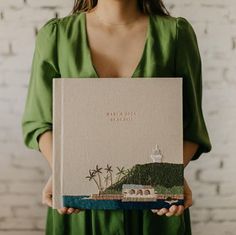 a woman holding a book with an image of a lighthouse on it