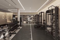 an empty gym with rows of exercise equipment and lights on the ceiling is lit by recessed lighting