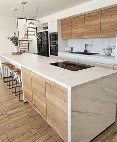 a modern kitchen with an island countertop and stools in front of the sink