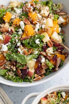 a salad in a bowl with apples, pecans and feta cheese on top