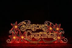 a sign that says seasons greetings lit up in the dark with christmas lights on it