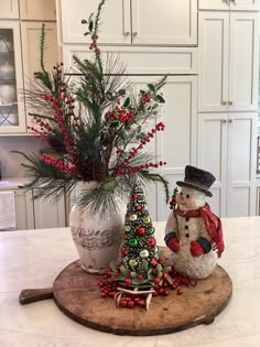 a snowman and christmas tree sitting on top of a kitchen counter next to a potted plant