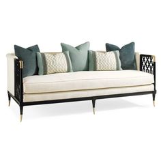 a white couch with pillows on it and some black metal frame around the armrests