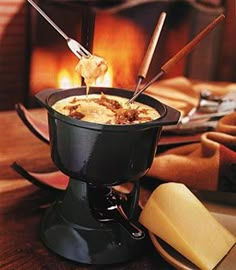 a fondue pot filled with food next to a fireplace