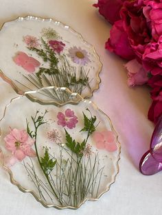 two plates with flowers painted on them next to some pink flowers