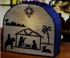 a cross stitch nativity scene is displayed on a table