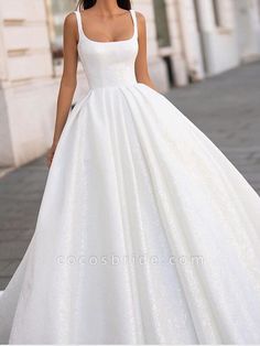 a woman in a white wedding dress is walking down the street with her hand on her hip