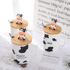 two coffee mugs with cows on them sitting next to each other in front of a menu