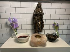 there is a statue, bowl and bread on the counter next to eachother