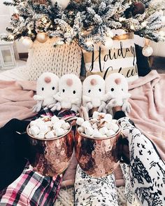 two little white kittens sitting on top of some boots next to a christmas tree