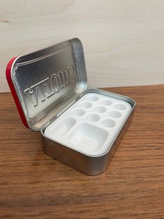 an empty tin with six compartments on a wooden table