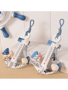 two miniature boats are attached to hooks on the wall with seashells hanging from them